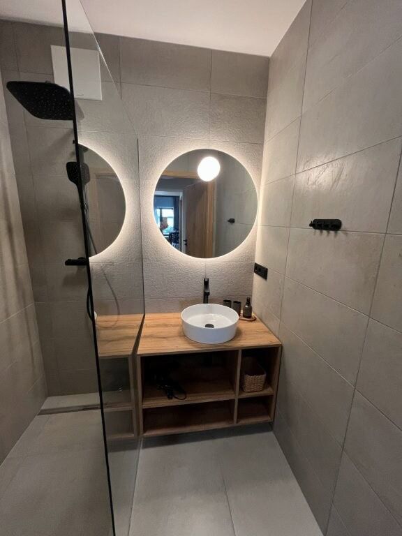Luxury bathroom with round mirrors, vessel sink, and minimalist design.