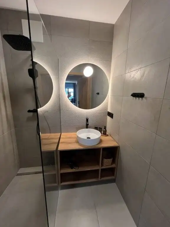 Luxury bathroom with round mirrors, vessel sink, and minimalist design.