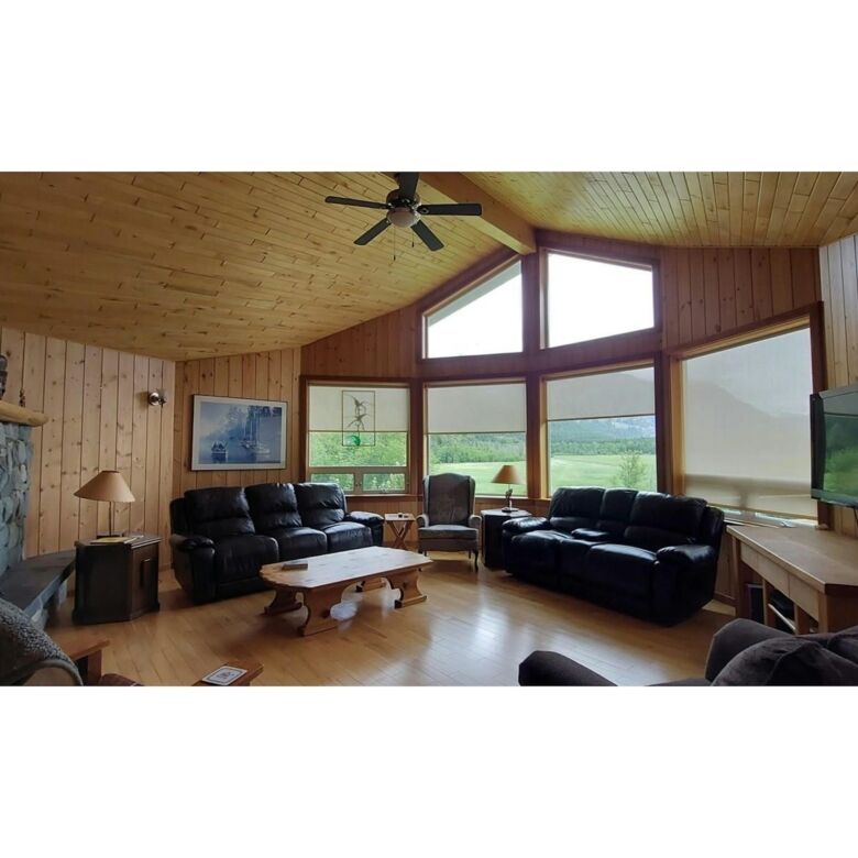 Spacious living room with large windows offering stunning views in this Bella Coola estate. Perfect.