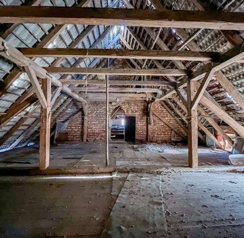 Attic space with wooden beams and brick walls in Lubiechowa for redevelopment.