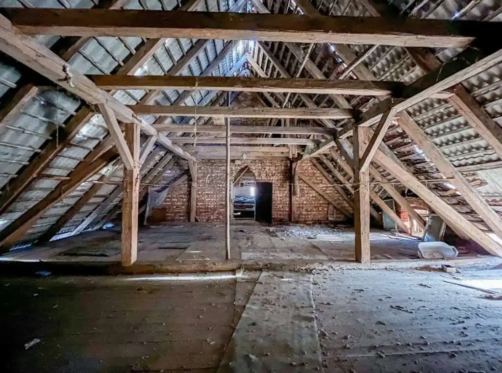 Attic space with wooden beams and brick walls in Lubiechowa for redevelopment.