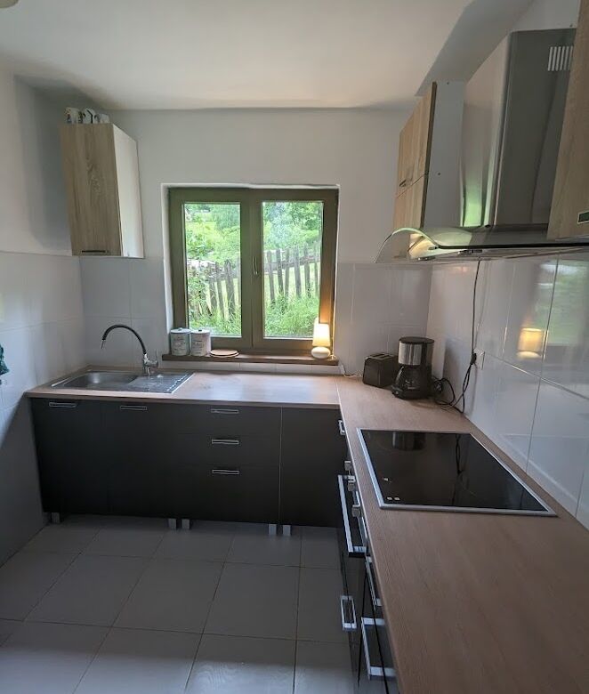 Modern kitchen in a Bicaz property for sale, featuring sleek cabinets, a window view of greenery, an.
