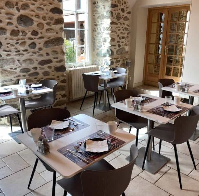 Bright breakfast area with stone walls and large windows in Ausson, Haute Garonne.