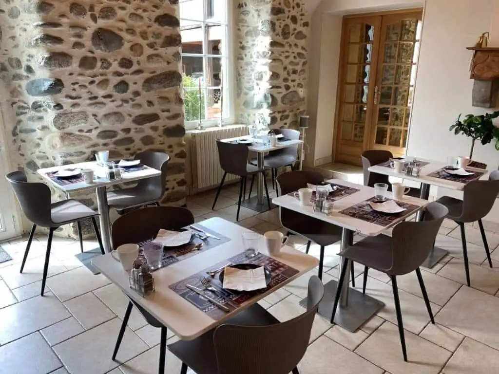 Bright breakfast area with stone walls and large windows in Ausson, Haute Garonne.