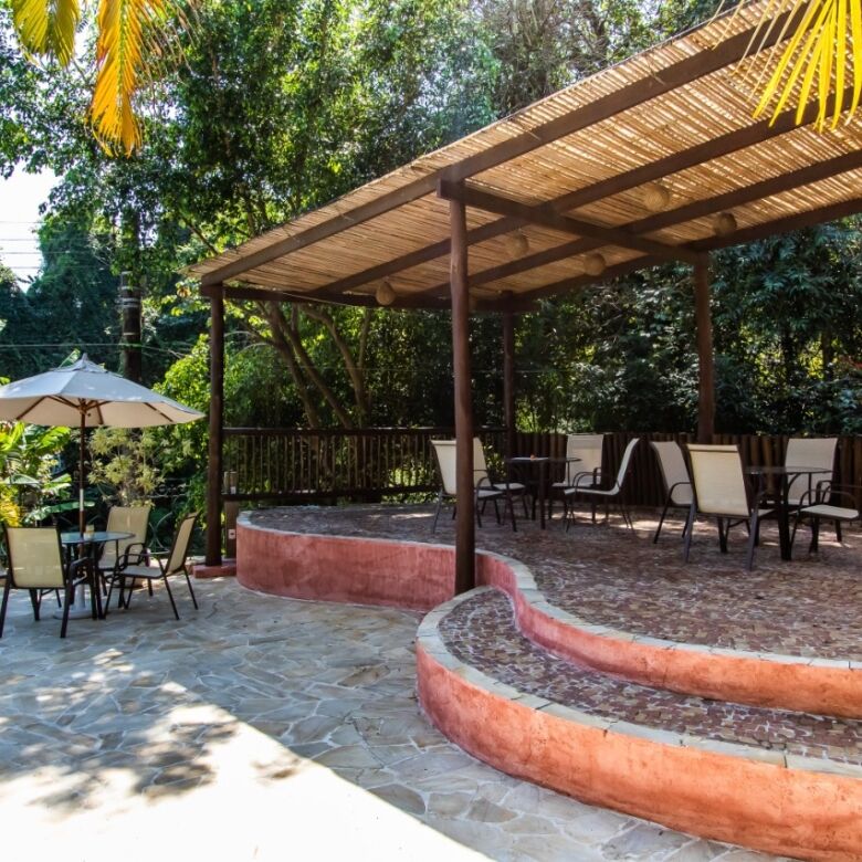 Beautiful outdoor seating area at a boutique hotel in Ilhabela, featuring shaded patio and lush trop.