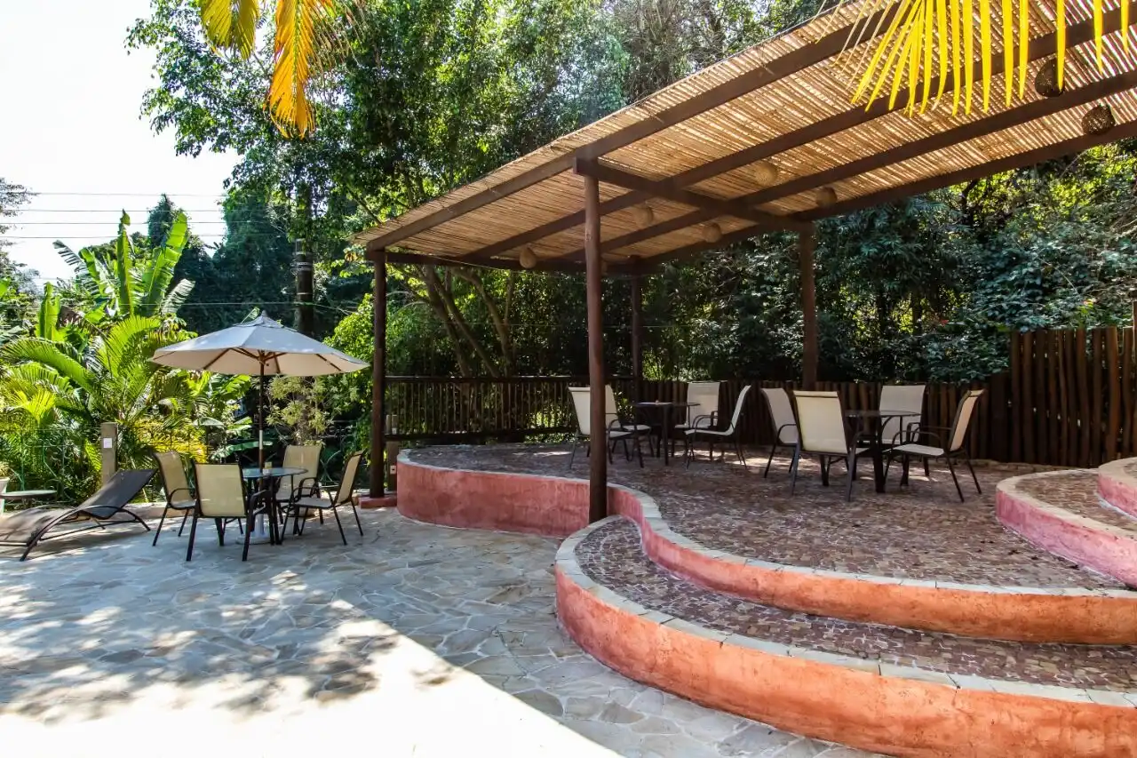 Beautiful outdoor seating area at a boutique hotel in Ilhabela, featuring shaded patio and lush trop.