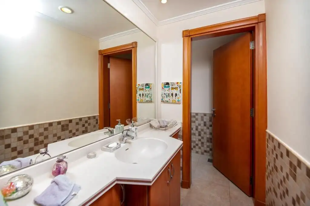 Bright bathroom with wooden door, mirror, and elegant decor in a high-end property.
