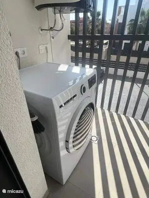 Washing machine installed on a balcony with safety railing in a modern apartment.