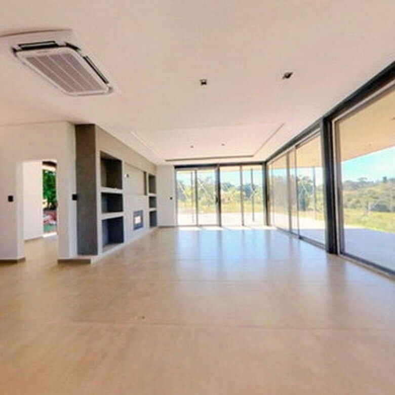 Spacious modern living room with large glass windows overlooking the pool and scenic outdoor landsca.
