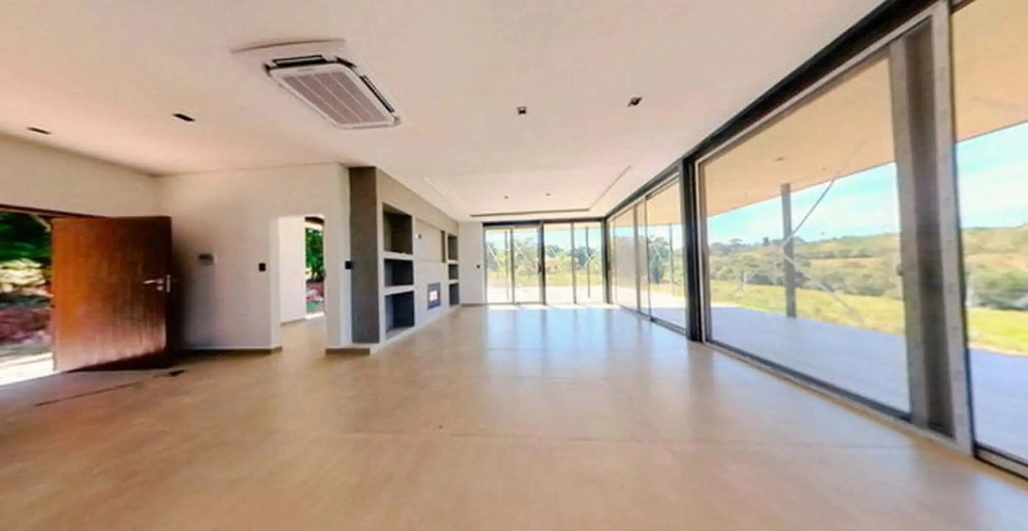 Spacious modern living room with large glass windows overlooking the pool and scenic outdoor landsca.