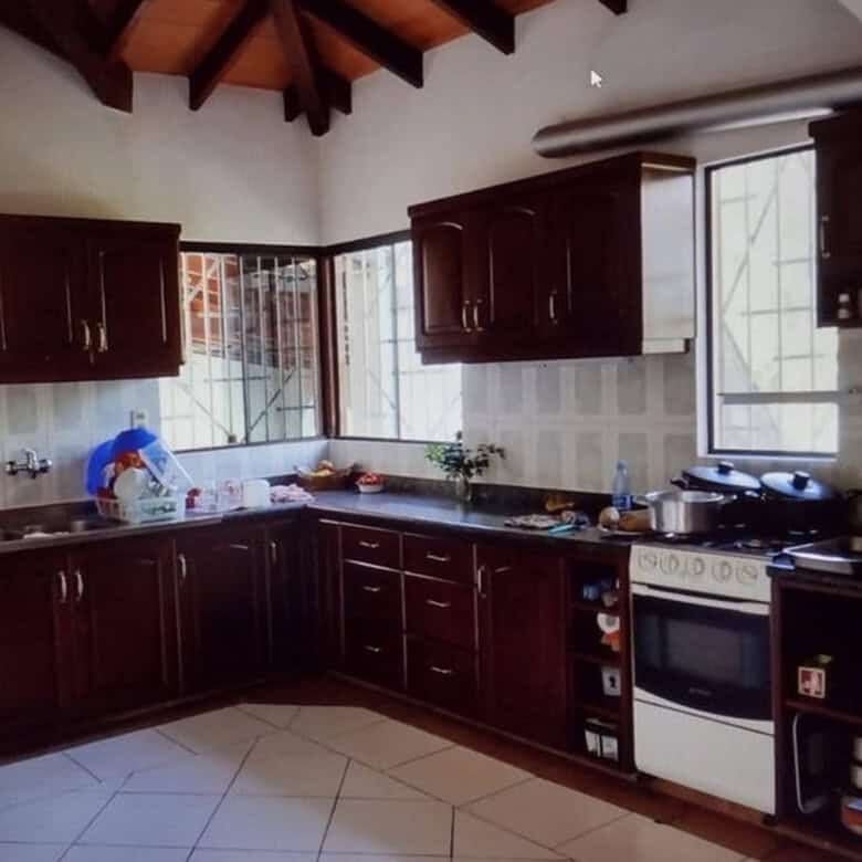 Spacious kitchen in a property with two houses and land in Pirayu, Paraguay, featuring dark wood cab.