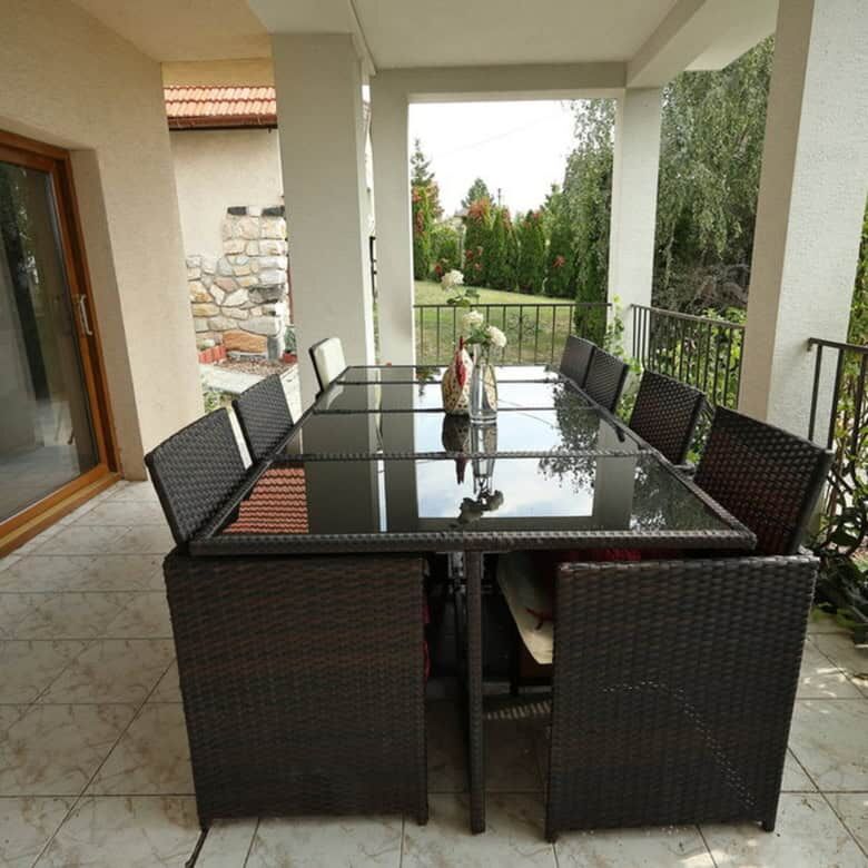 Outdoor dining area with a glass table and wicker chairs overlooking the vineyard in Vinica, Slovaki.