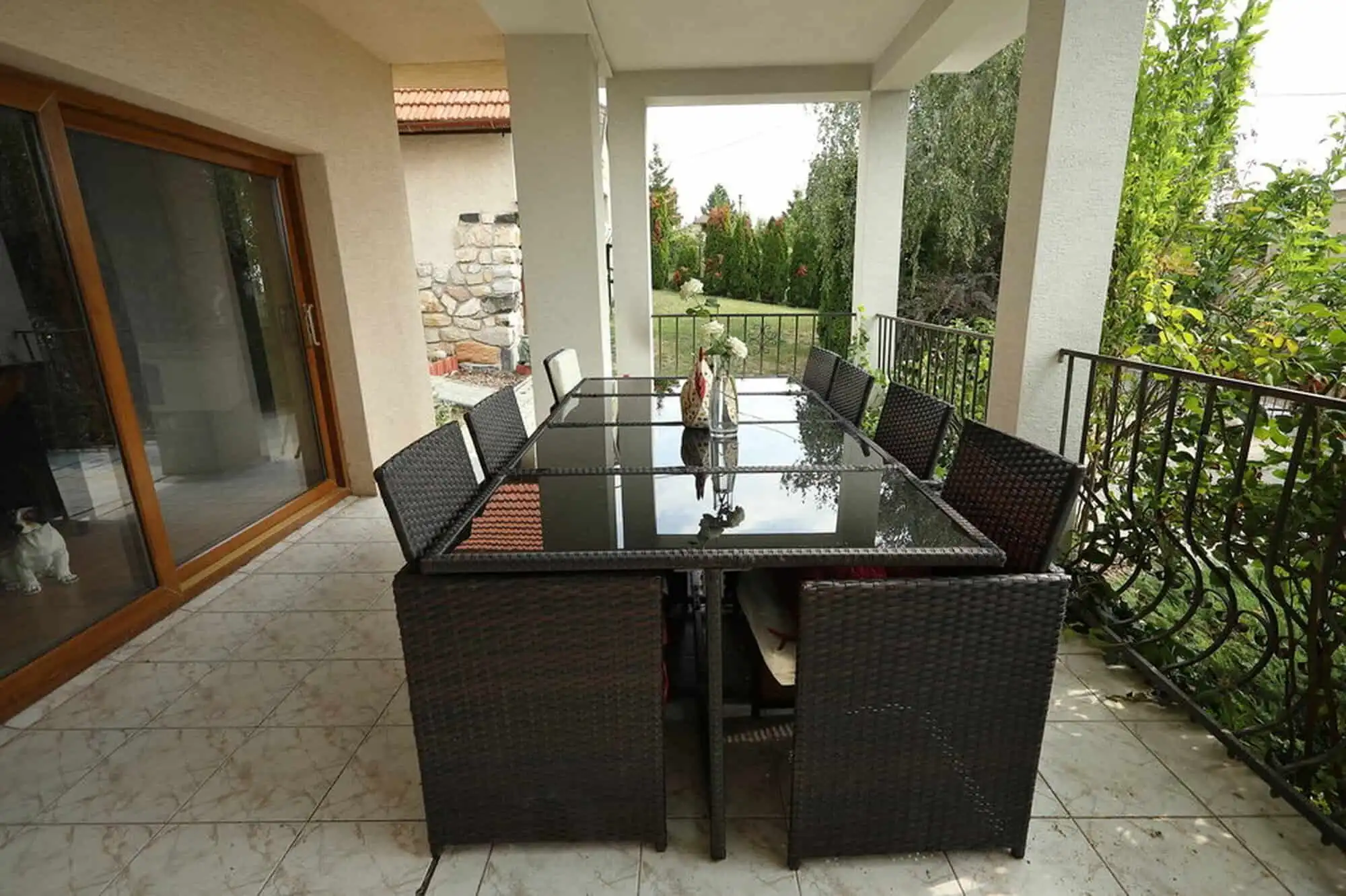Outdoor dining area with a glass table and wicker chairs overlooking the vineyard in Vinica, Slovaki.