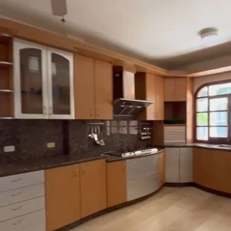 Modern kitchen with wooden cabinets, stainless steel appliances, and a large window offering natural.