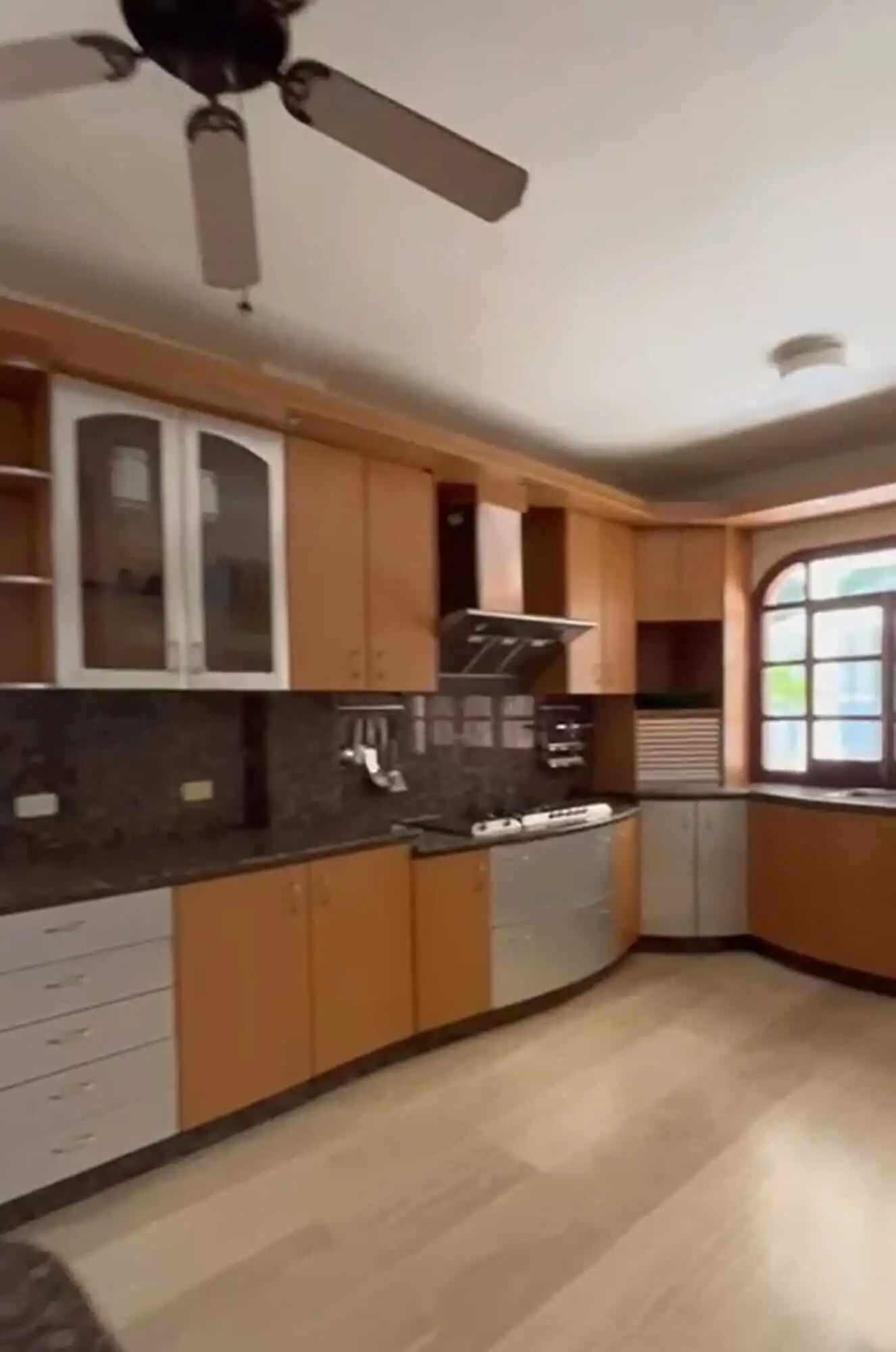 Modern kitchen with wooden cabinets, stainless steel appliances, and a large window offering natural.