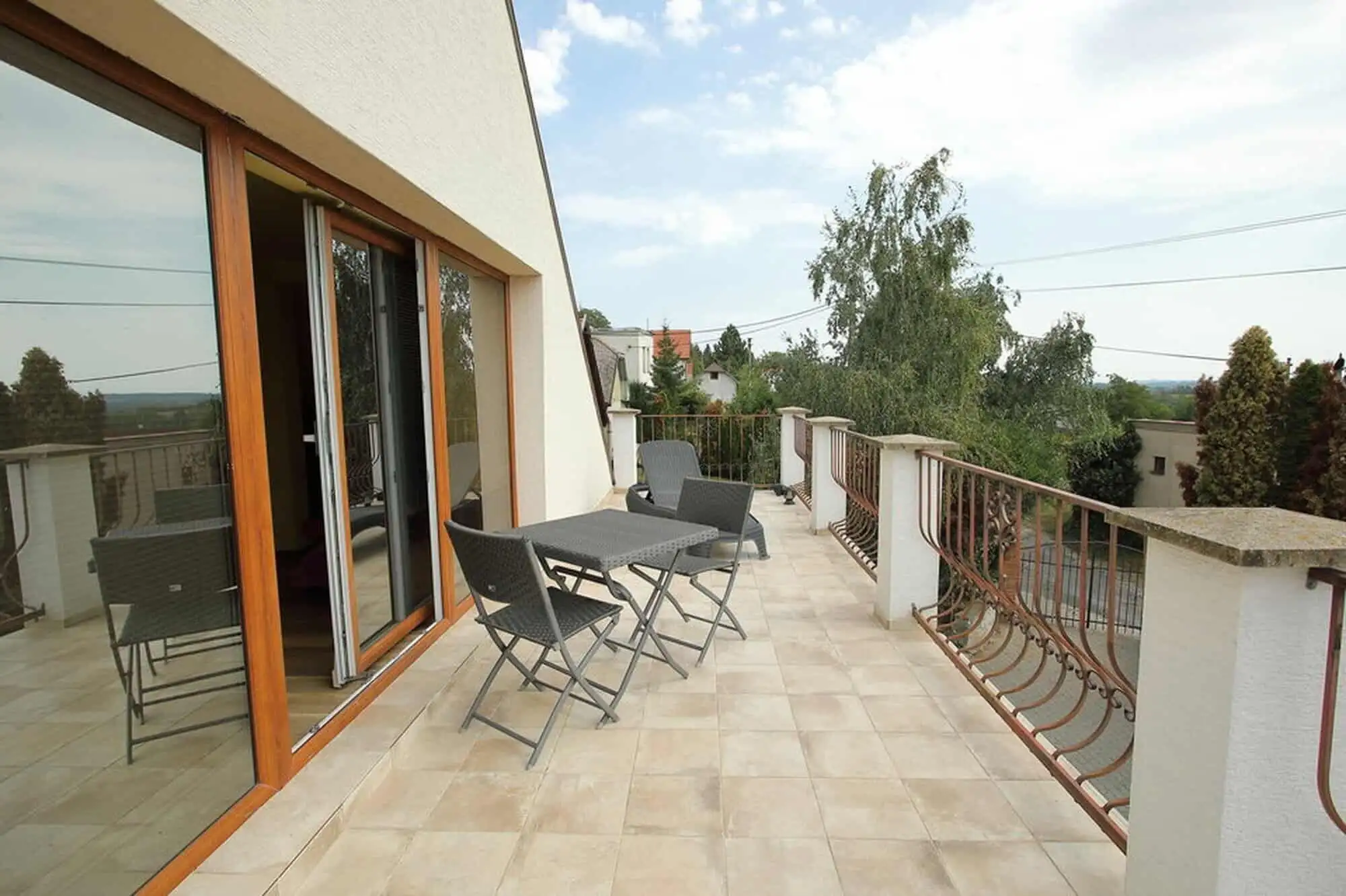 Balcony with outdoor seating overlooking vineyards and surrounding landscape in Vinica, Slovakia.