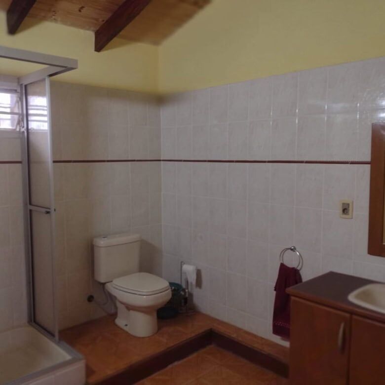 Spacious bathroom with toilet, sink, and shower in a property located in Pirayu, Paraguay.
