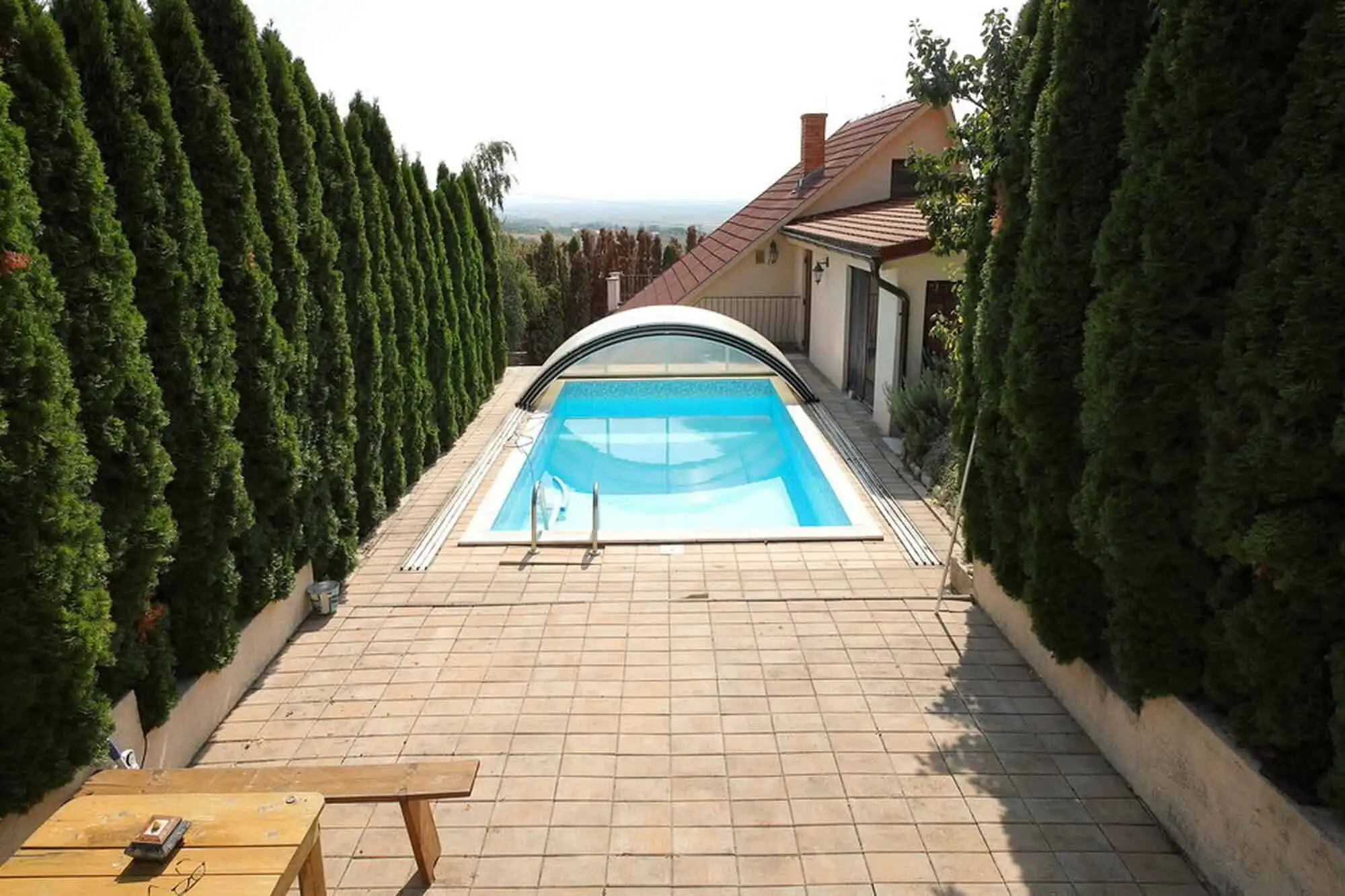 Outdoor swimming pool with surrounding terrace and lush greenery in Vinica, Slovakia.