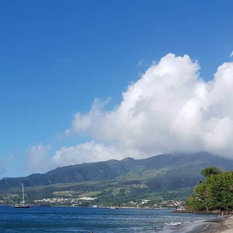 Scenic beach on Martinique island with clear waters and green hills in the background.