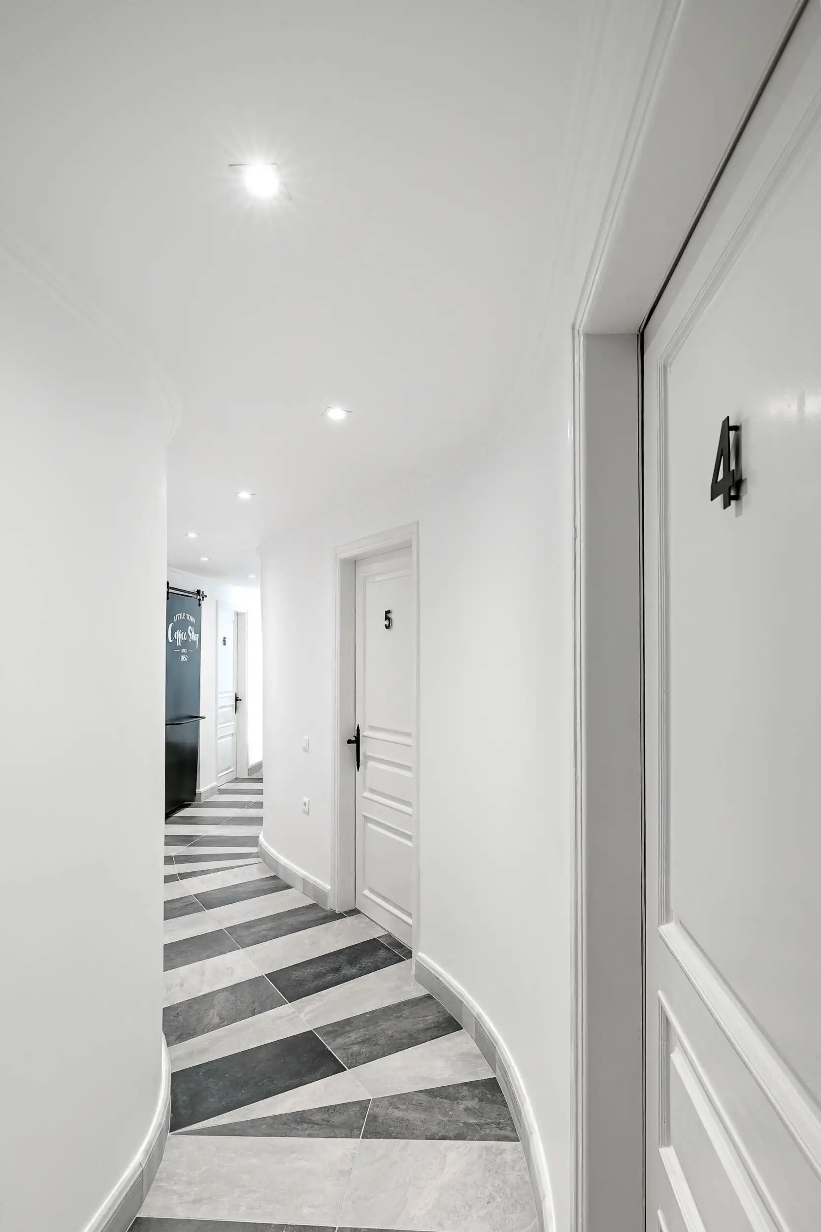 Modern white hallway with stylish flooring and doorways in a luxury villa. Elegant corridor featuring white walls, contemporary design, and patterned flooring.