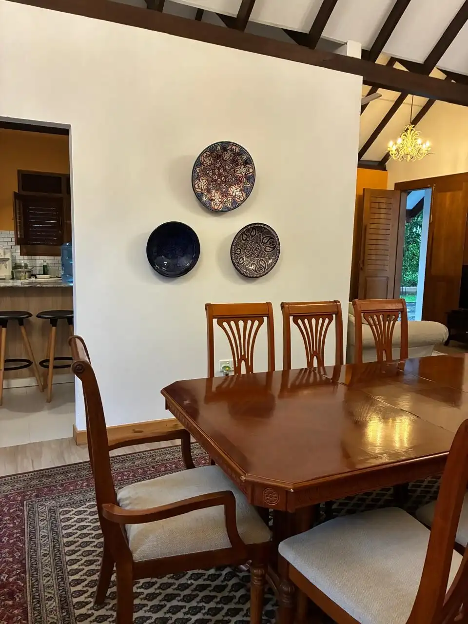 Elegant dining room featuring a wooden table and chairs, decorated with artistic wall plates in a co.
