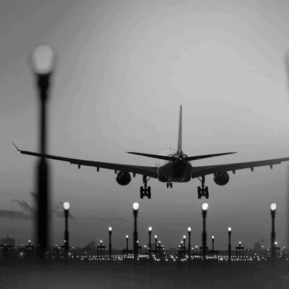 Modern airport with airplane landing at dusk, city skyline in background.