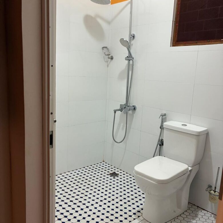 Bathroom with shower, toilet, and white tiles in Waikkal estate.