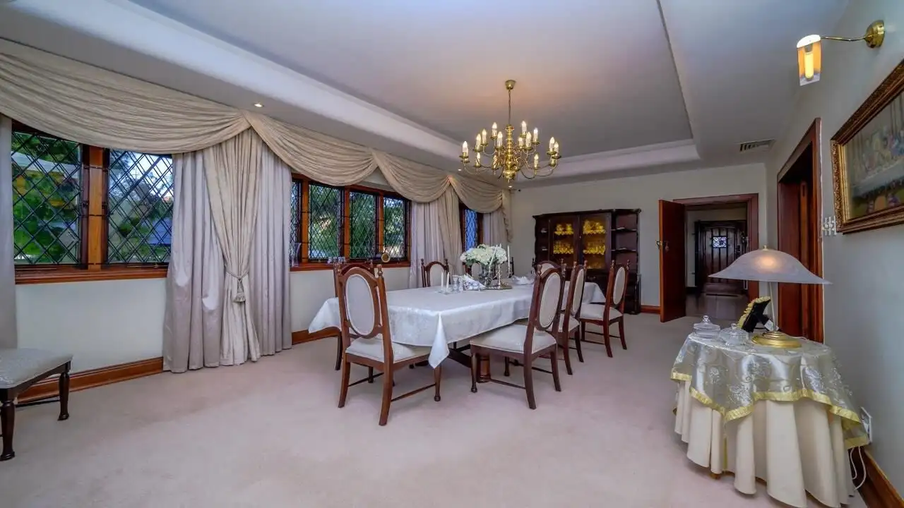 Elegant dining room in a luxury 9-bedroom estate in Durban South. Features classic decor, large wind.