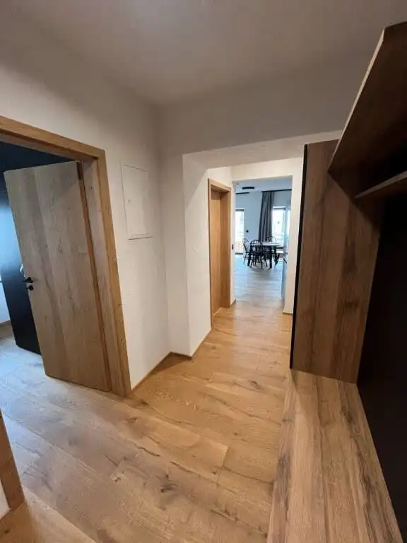 Spacious hallway with wooden flooring leading to living and dining areas in a luxury Rattendorf apar.