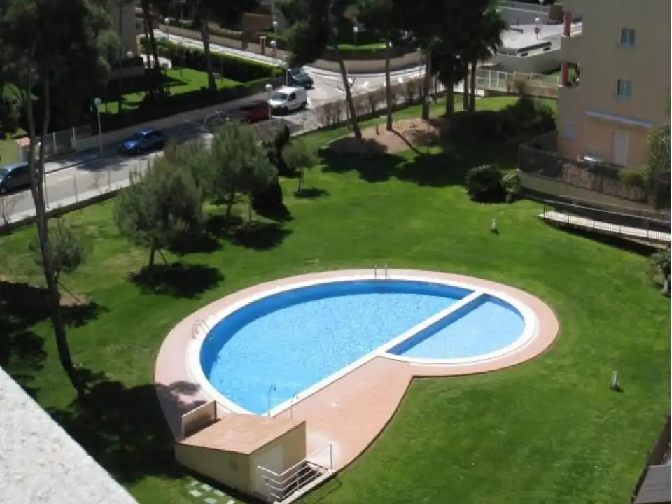 Apartment with swimming pool and lush green outdoor space.