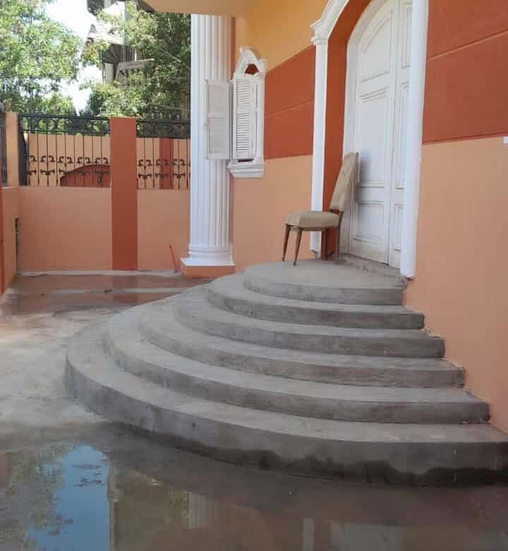 Elegant entrance with curved steps leading to a white door in a peach-colored building.