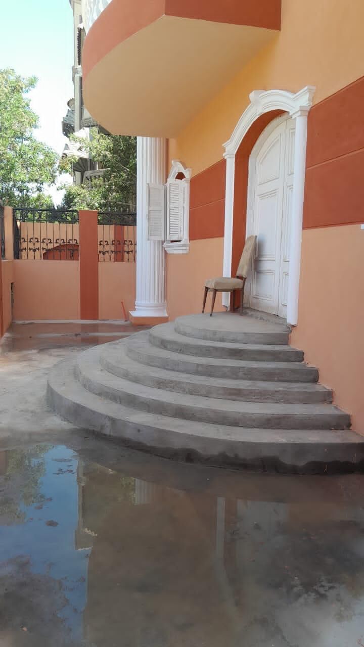 Elegant entrance with curved steps leading to a white door in a peach-colored building.