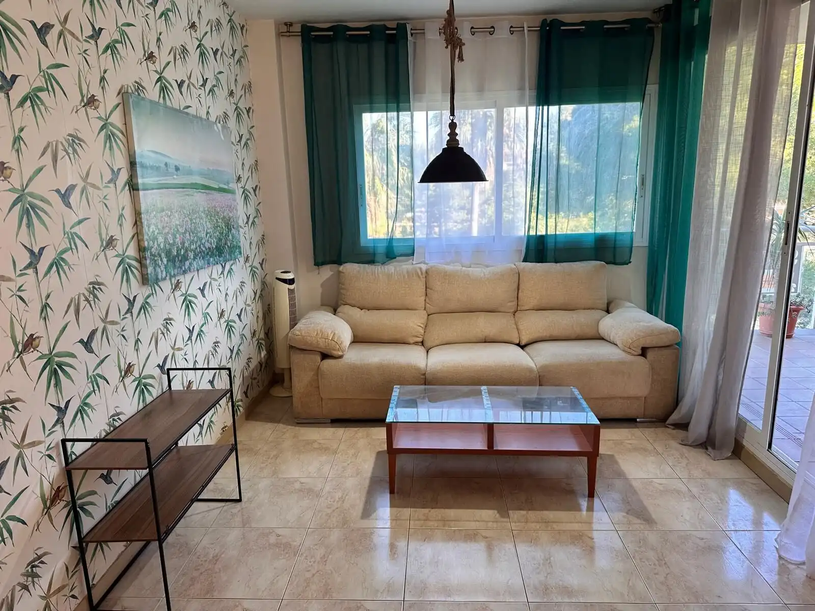 Bright living room with large windows and a beige sofa, perfect for relaxing in a spacious apartment.