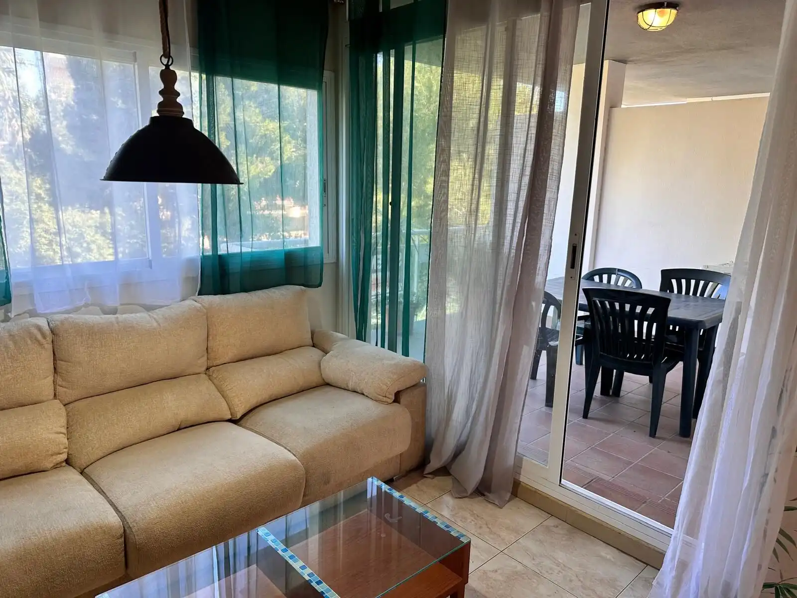 Bright living room with beige sofa and large windows overlooking balcony. Perfect for relaxing and e.