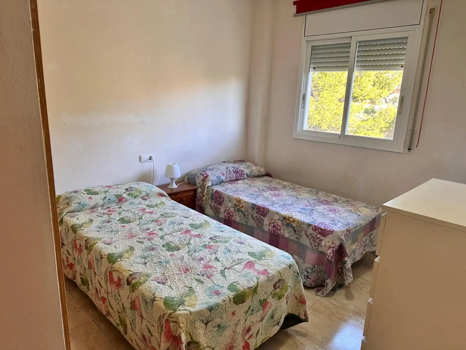 Comfortable bedroom in a 6/7-person tourist apartment with two single beds and a window with a view.
