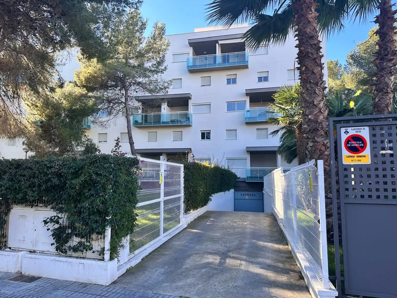 Apartment building with balconies, surrounded by trees and greenery.