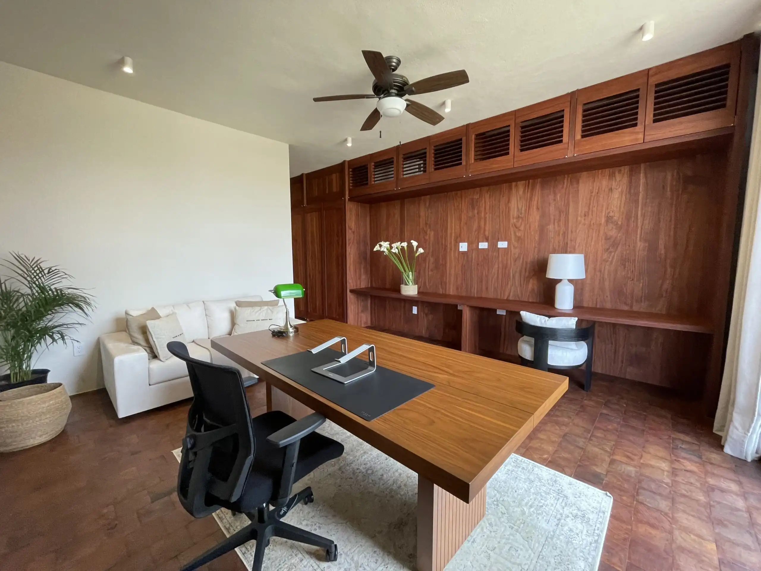 Modern Home Office with Wooden Wall Paneling and Desk Stylish home office featuring wooden wall paneling, a large desk, and comfortable seating.