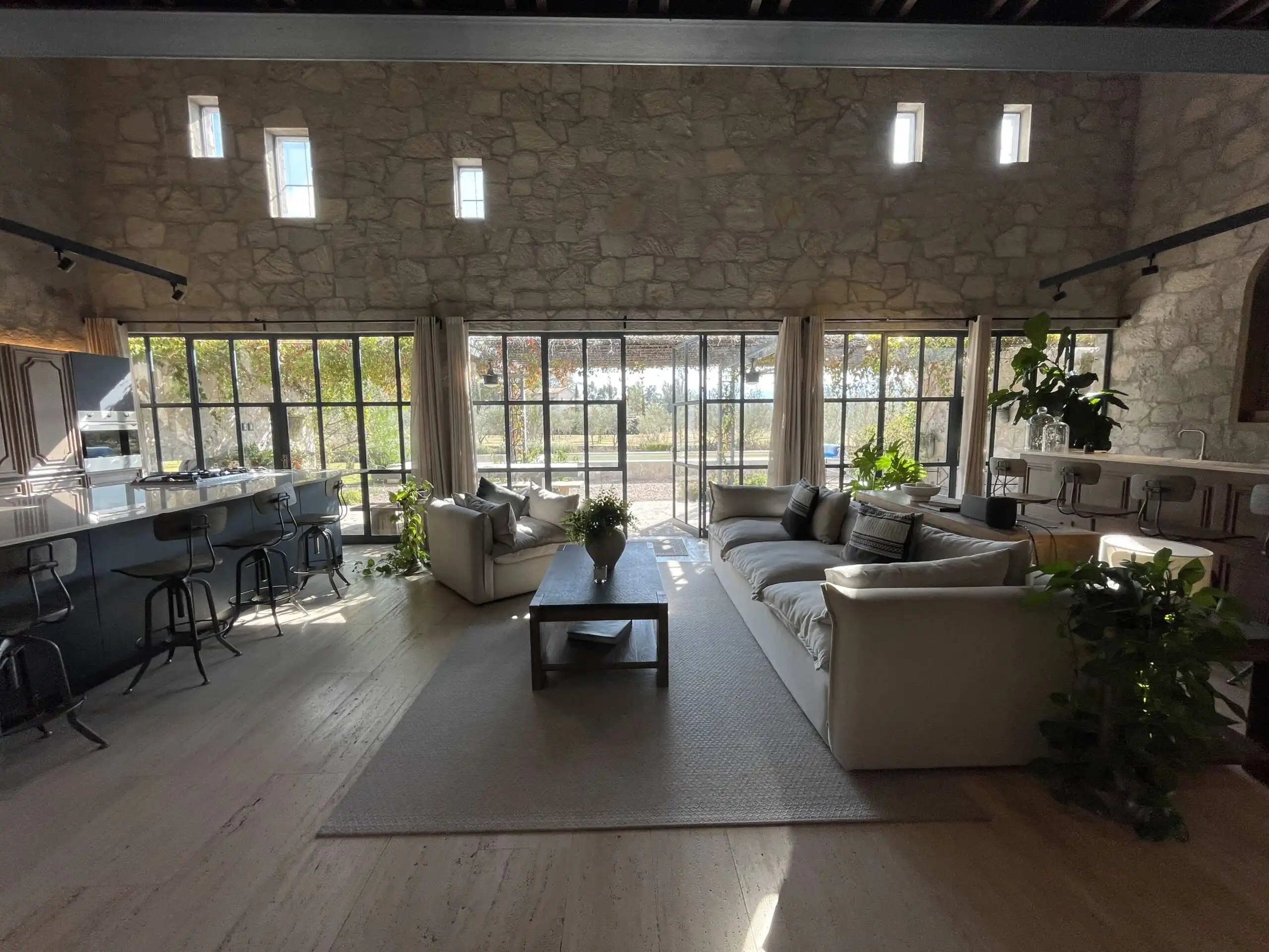 Elegant living room with stone walls and large windows overlooking vineyards.