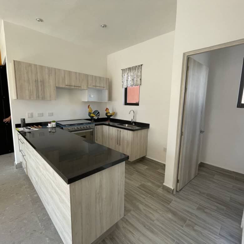 Spacious kitchen with light wood cabinets and black countertops.