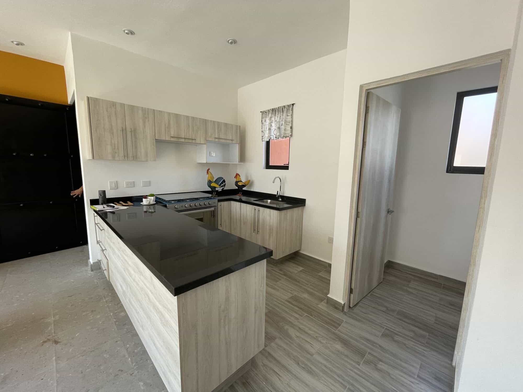 Spacious kitchen with light wood cabinets and black countertops.