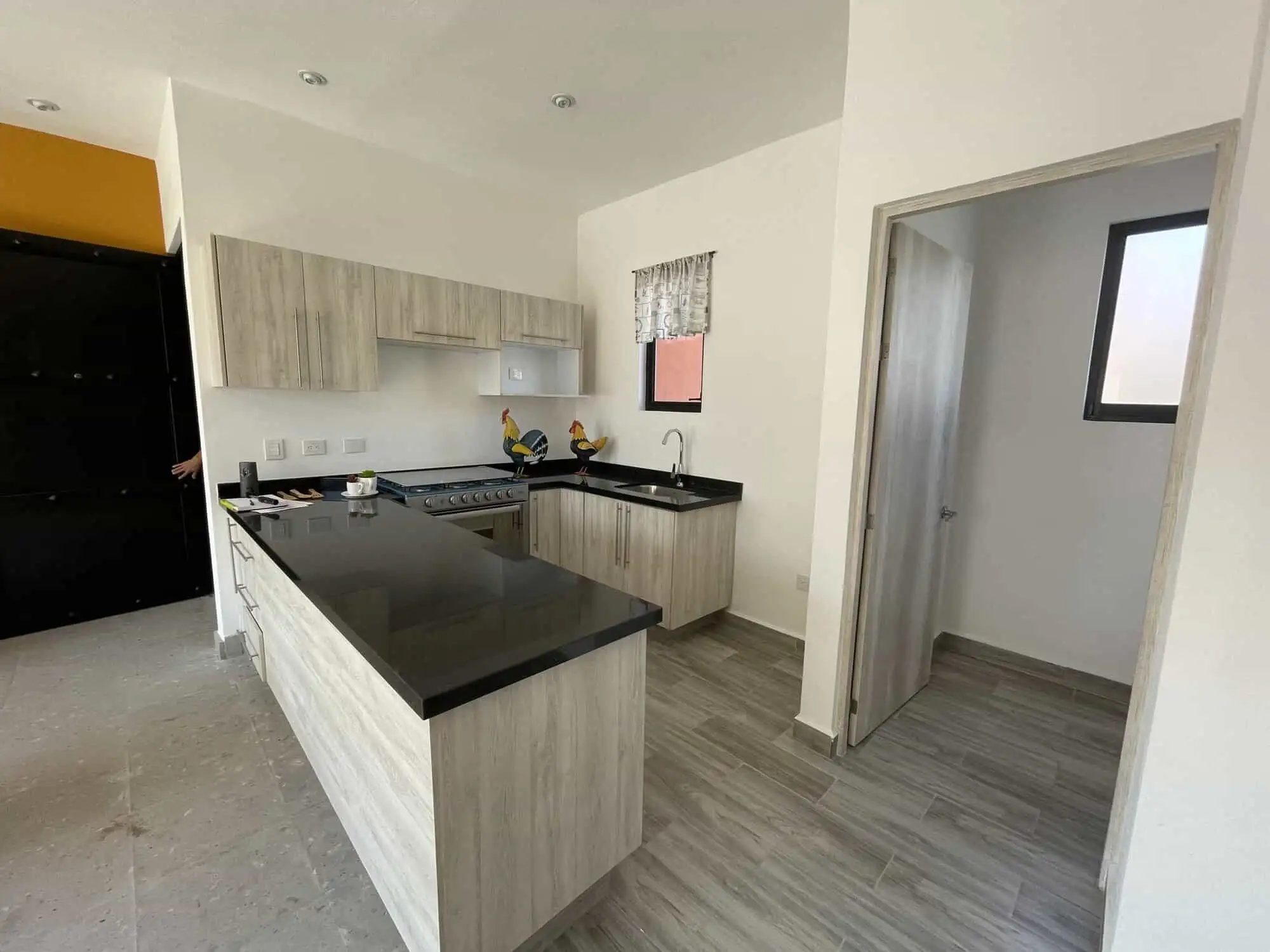 Spacious kitchen with light wood cabinets and black countertops.