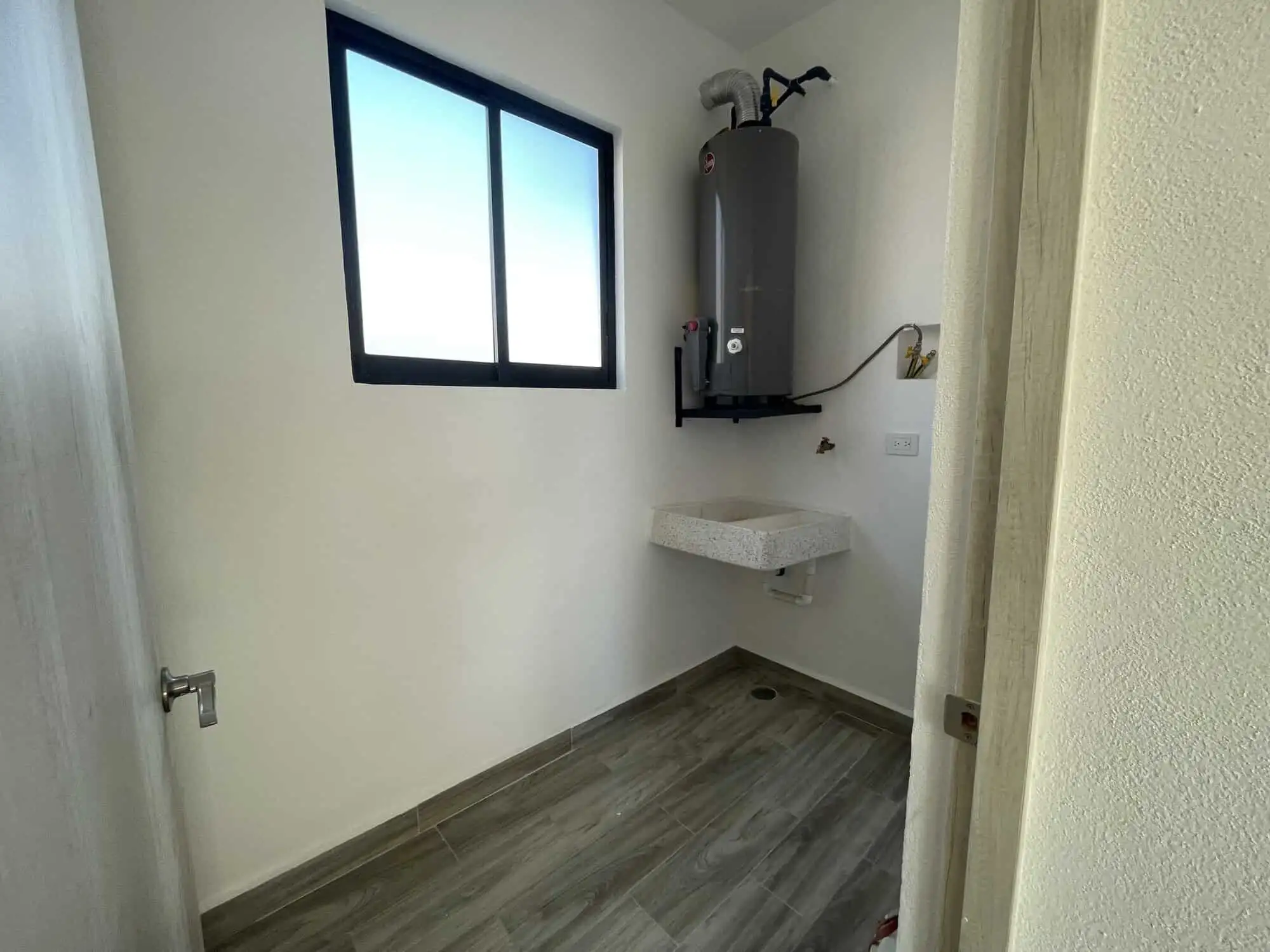 Laundry area with water heater and utility sink in a modern home.
