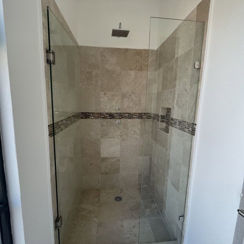 Spacious bathroom shower with glass door and beige tile walls in La Serena Residencial.
