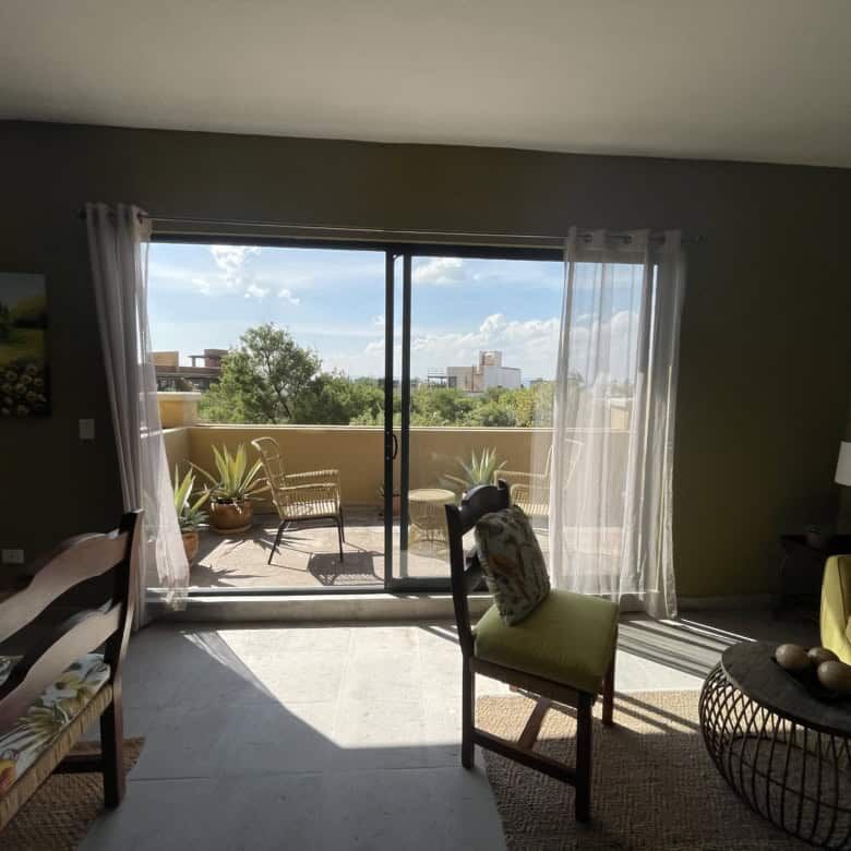 Bright living room with sliding glass doors opening to a balcony in Santo Domingo home. Elegant furn.