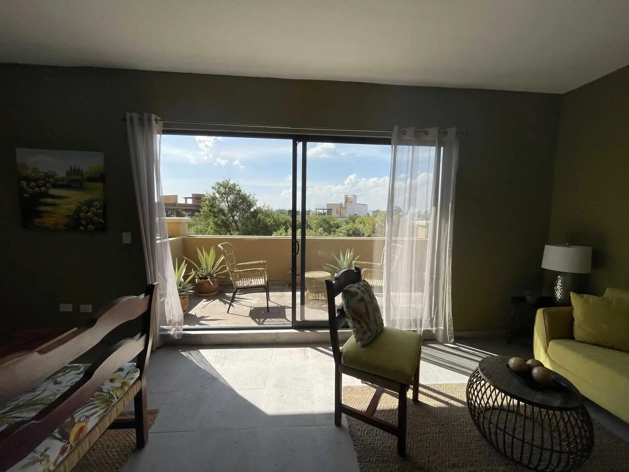 Bright living room with sliding glass doors opening to a balcony in Santo Domingo home. Elegant furn.