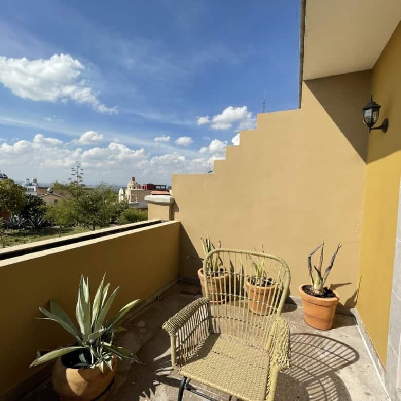 Balcony view of a modern colonial house in Santo Domingo with potted plants and outdoor seating.