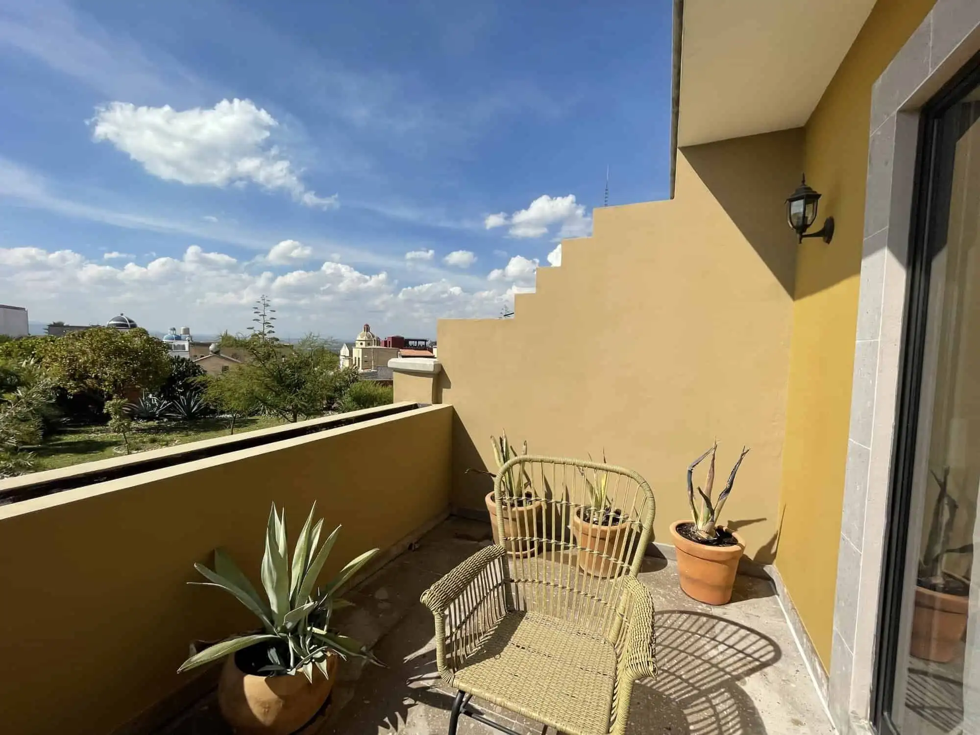 Balcony view of a modern colonial house in Santo Domingo with potted plants and outdoor seating.