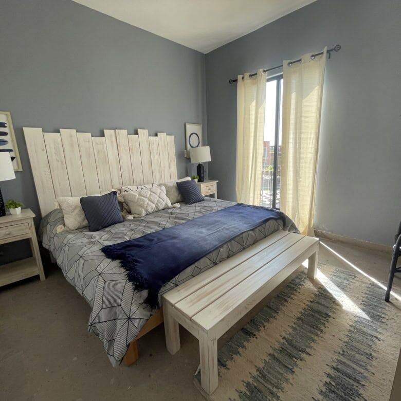 Bedroom with light blue walls, large windows, and stylish decor in a modern house.