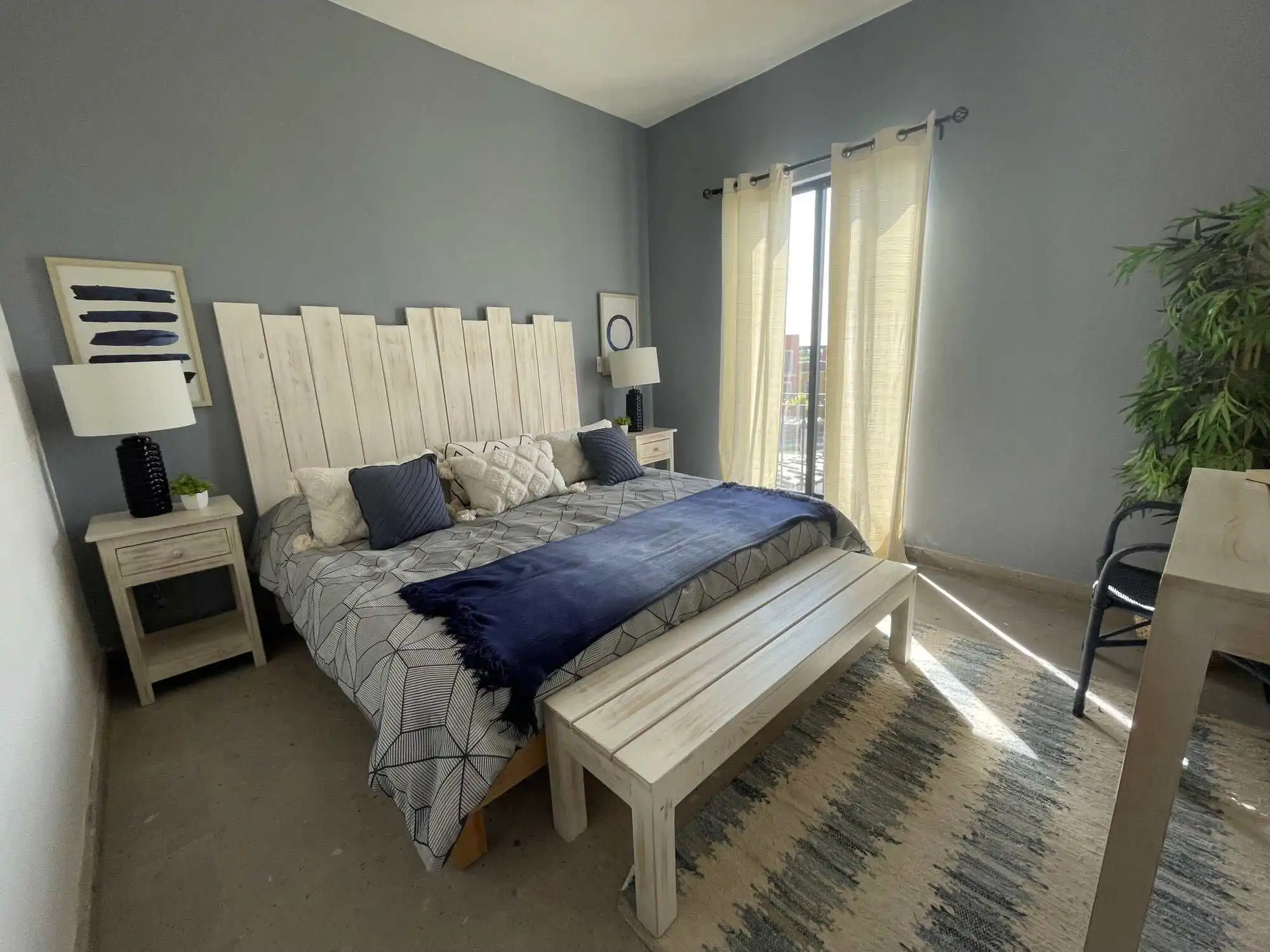 Bedroom with light blue walls, large windows, and stylish decor in a modern house.