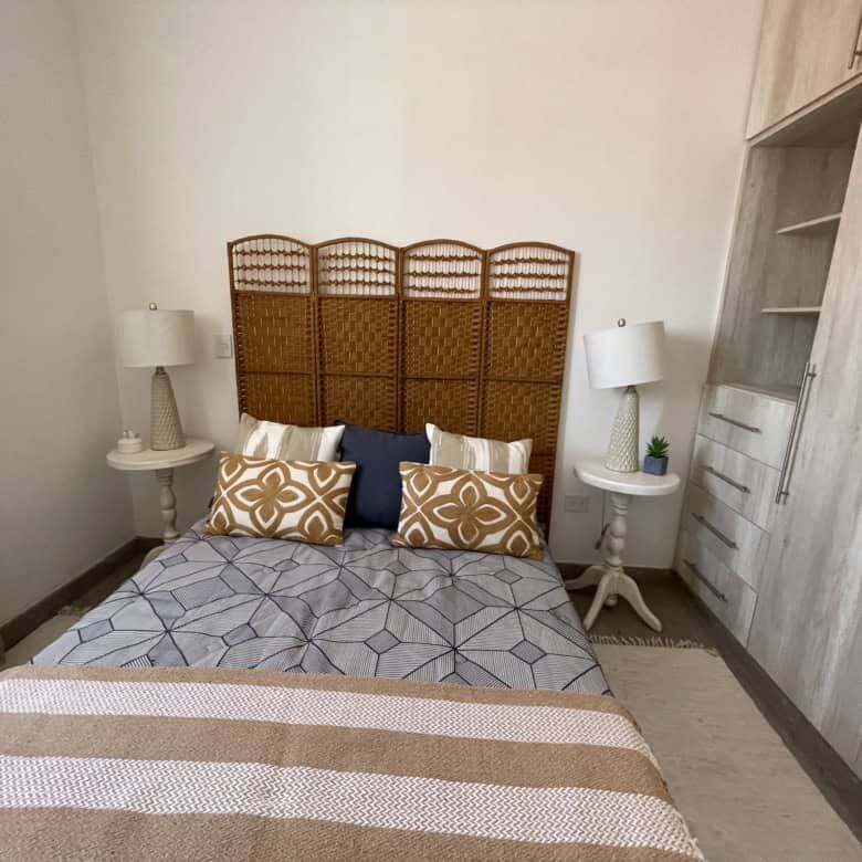Cozy bedroom with modern decor and rattan headboard in Santo Domingo home.